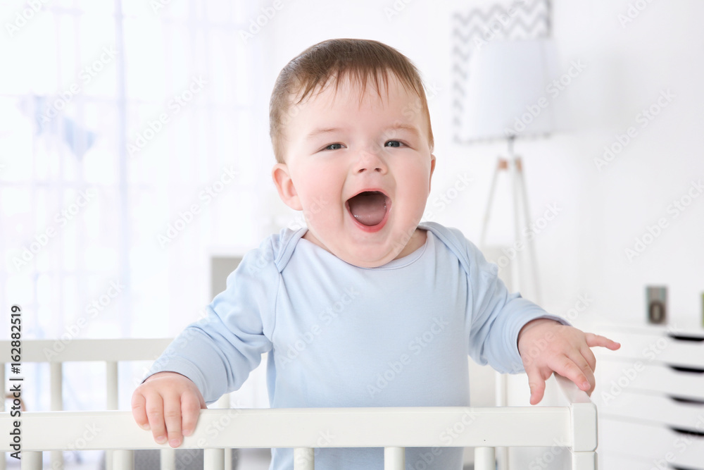 Cute little baby standing in crib at home Cute little baby standing in crib at home