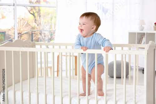 Cuadro en lienzo Cute little baby standing in crib at home