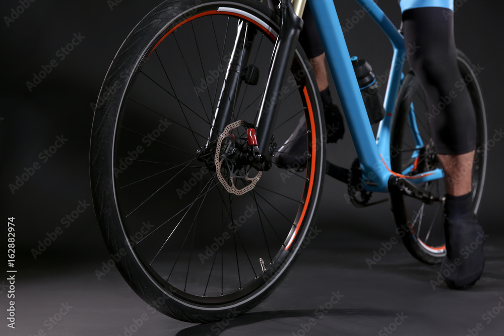 Legs of young sporty cyclist riding bicycle on dark background Legs of young sporty cyclist riding bicycle on dark background