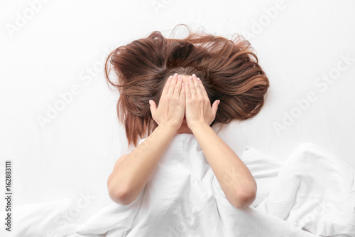 Young woman lying in bed an...