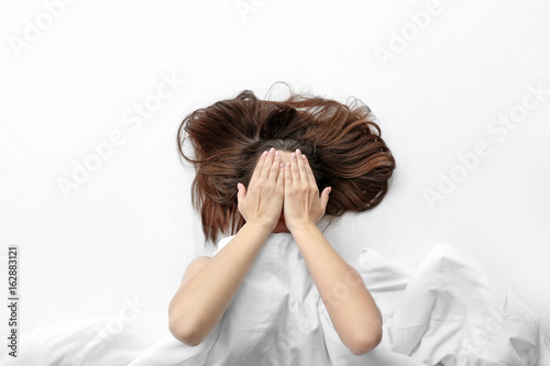 Young woman lying in bed an...