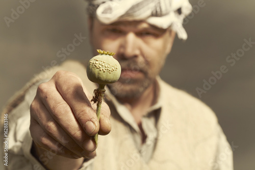 Canvas Print Middle East man posing when harvesting opium on poppy field