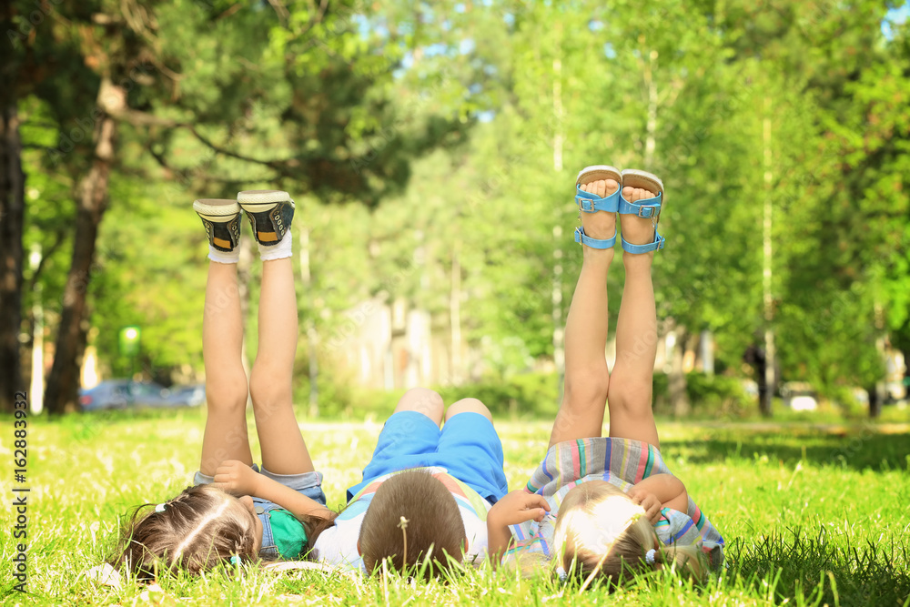 Cute little children lying on green grass in park Cute little children lying on green grass in park