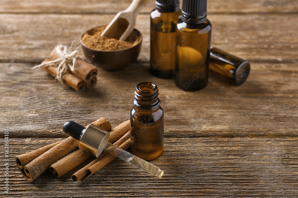Composition with bottle of cinnamon oil on wooden background