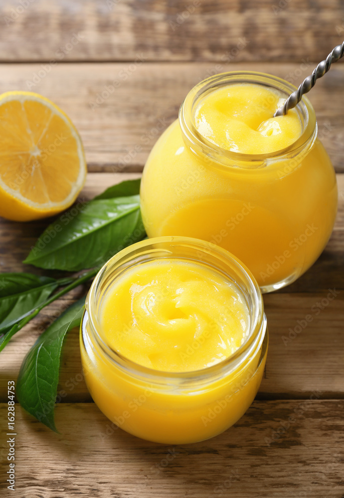 Glass jars with yummy lemon curd on wooden table Glass jars with yummy lemon curd on wooden table