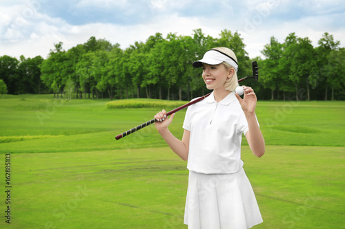 Beautiful young woman on golf course in summer day