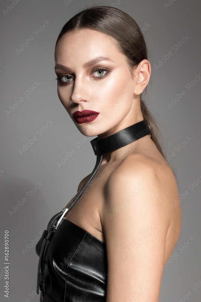 Awesome European attractive sexy fashion model with natural brunette hair, long eyelashes, full lips, perfect skin posing in studio, wearing black top, leather straps and belts, retouched image Awesome European attractive sexy fashion model with natural brunette hair, long eyelashes, full lips, perfect skin posing in studio, wearing black top, leather straps and belts, retouched image