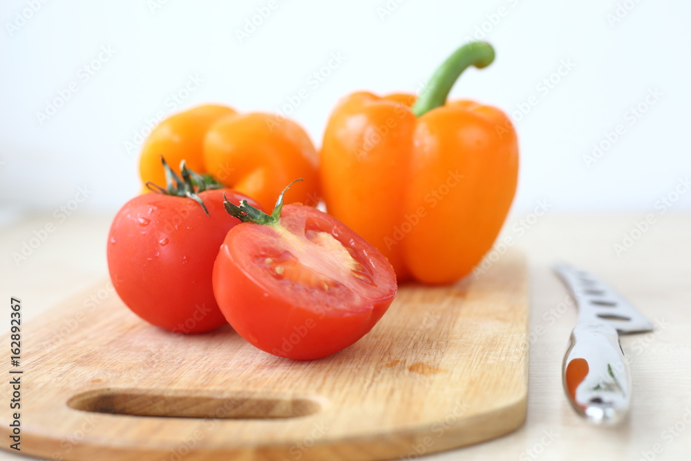 orange bell pepper, tomato and knife on Board orange bell pepper, tomato and knife on Board