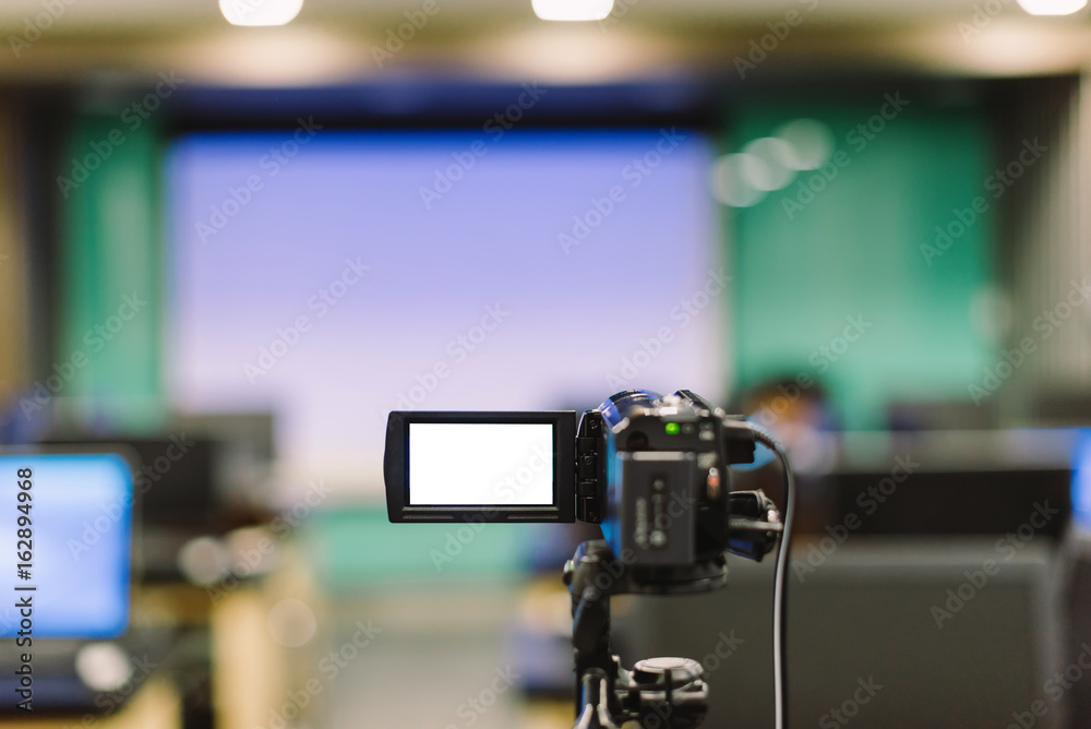 The video camera is recording the lecture in the conference room in selective focus.