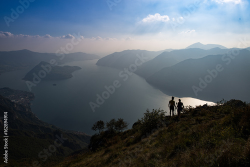 A couple of hikers look at the panorama of Lake Isea in Italy photo