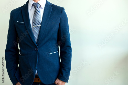 business man in blue suit standing on a concrete wall background