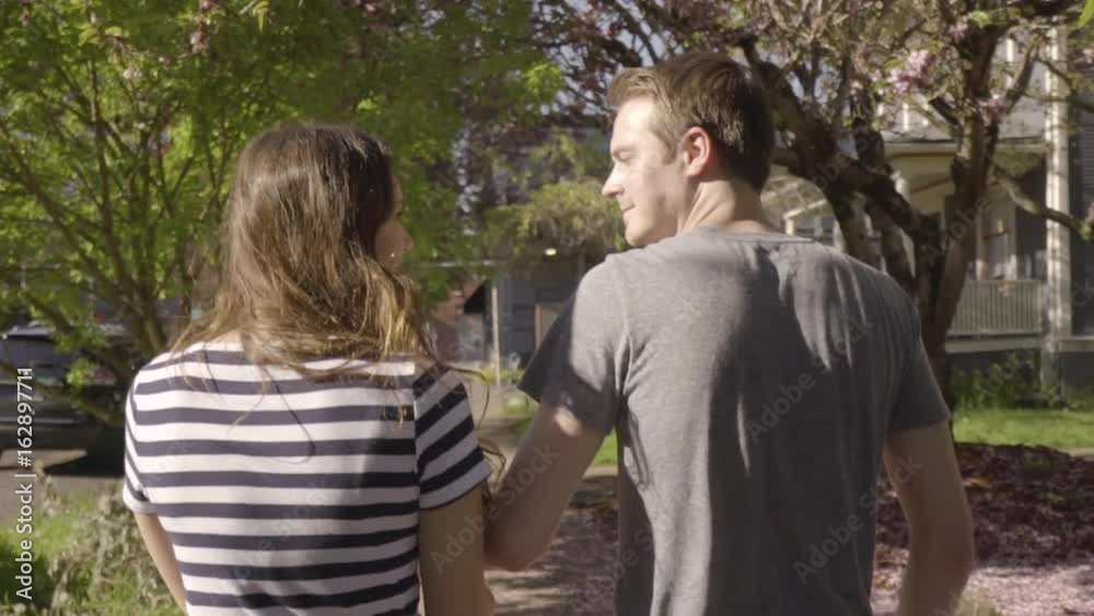 Cute Couple Walk (Away From Camera) Around City Neighborhood, Man Twirls His Girlfriend (Slow Motion) Cute Couple Walk (Away From Camera) Around City Neighborhood, Man Twirls His Girlfriend (Slow Motion)