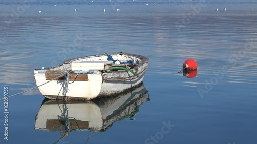 Fethiye, Turkey - 19th of January, 2017:  4K Old small nameless boat reflected in water and a buoy photo