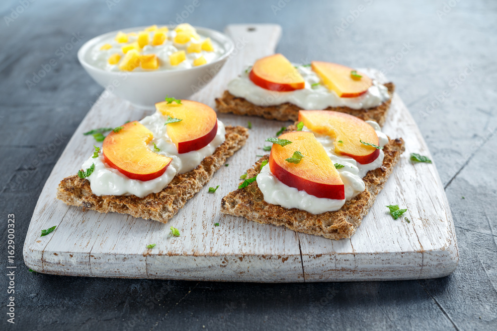 Homemade Crispbread toast with Cottage Cheese and nectarine on white wooden board.