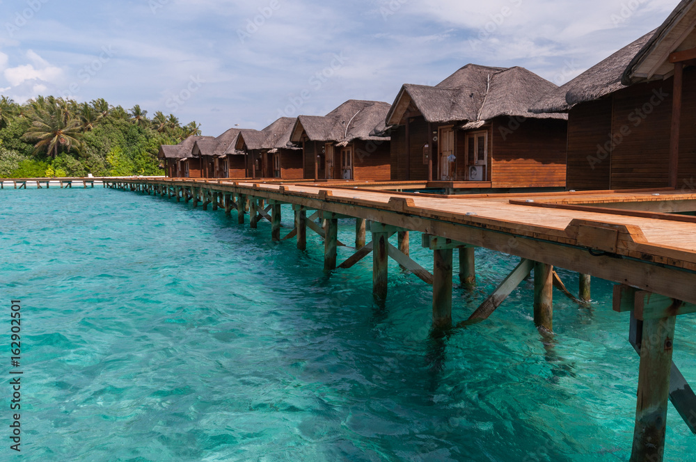 Tropical Maldives island resort with luxury water villas and wooden bridge