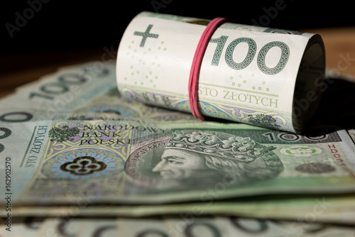 Roll and stack of Polish Zloty banknotes (PLN) closeup. Polish One Hundred Zlotych bills