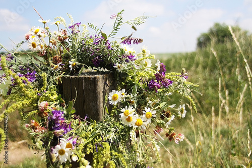 wreath of flowers hanging on a wooden stick on a wild field