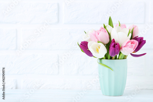 Fototapeta Naklejka Na Ścianę i Meble -  Bouquet of tulips in cup on brick wall background
