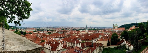 Panorama of the Prague (Praha) Cityscape / Skyline: Capital of the Czech Republic in Europe with houses with red roofs, churches and a light blue sky with white clouds