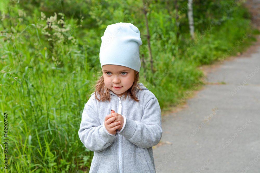 Little girl is walking in the summer forest