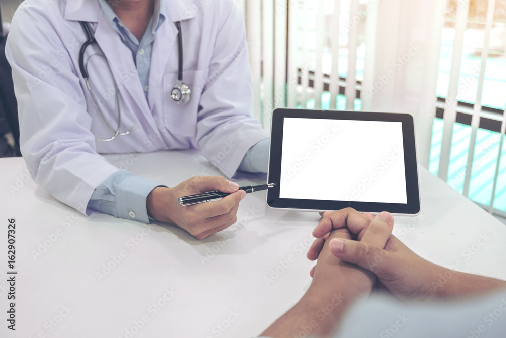Doctor consulting patient and recommend treatment methods and how to rehabilitate the body, presenting results on tablet computer in hospital office