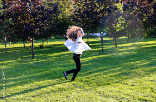 A young girl is spinning in the park for joy