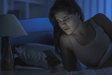 The sleepy woman lay with a phone on the bed. night time