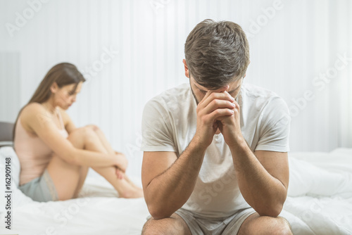 The man with impotence sit near the woman on the bed photo