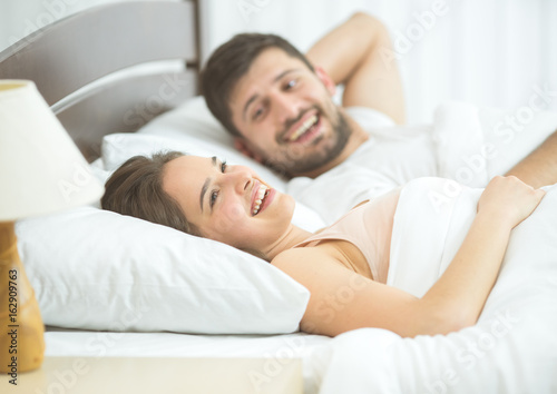 The happy couple lay in the comfortable bed