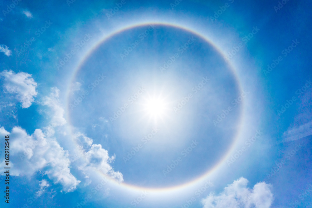 The Sun halo on the blue sky and clouds at noon