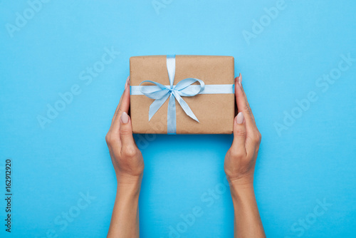 Woman hands holding gift wrapped and decorated with bow