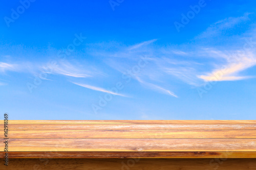 Empty wooden table with blue sky background.