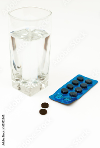 Activated carbon pills and glass of water.