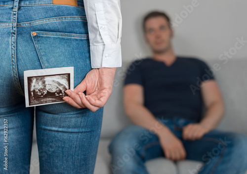 Surprise darling! Woman is hiding ultrasound picture behind her back.