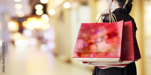 Quadro su tela Young woman holding red shopping bag at department store