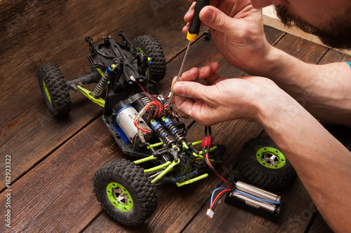 Rc radio control car crawler model toy electronics repair. Green toy suv in repairshop workplace, free space