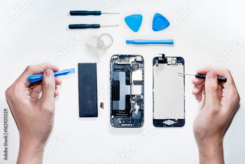 The smartphone was damages and need to repair  which tools smartphone that stand isolated on white background by hands of repairman. photo