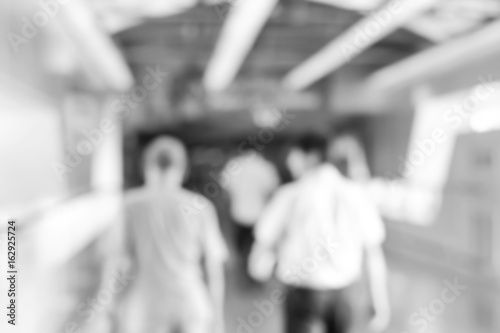 Blurred back view of people walking in corridor, monochrome effect