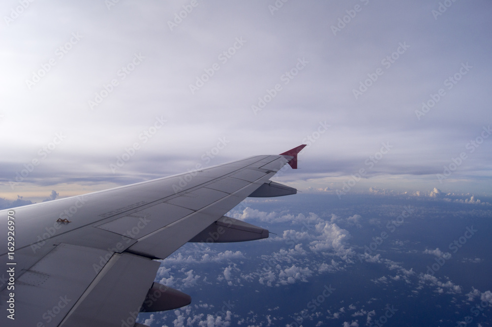 Through the windows of an airplane overlooking sunset on high altitude with visible red winglet.