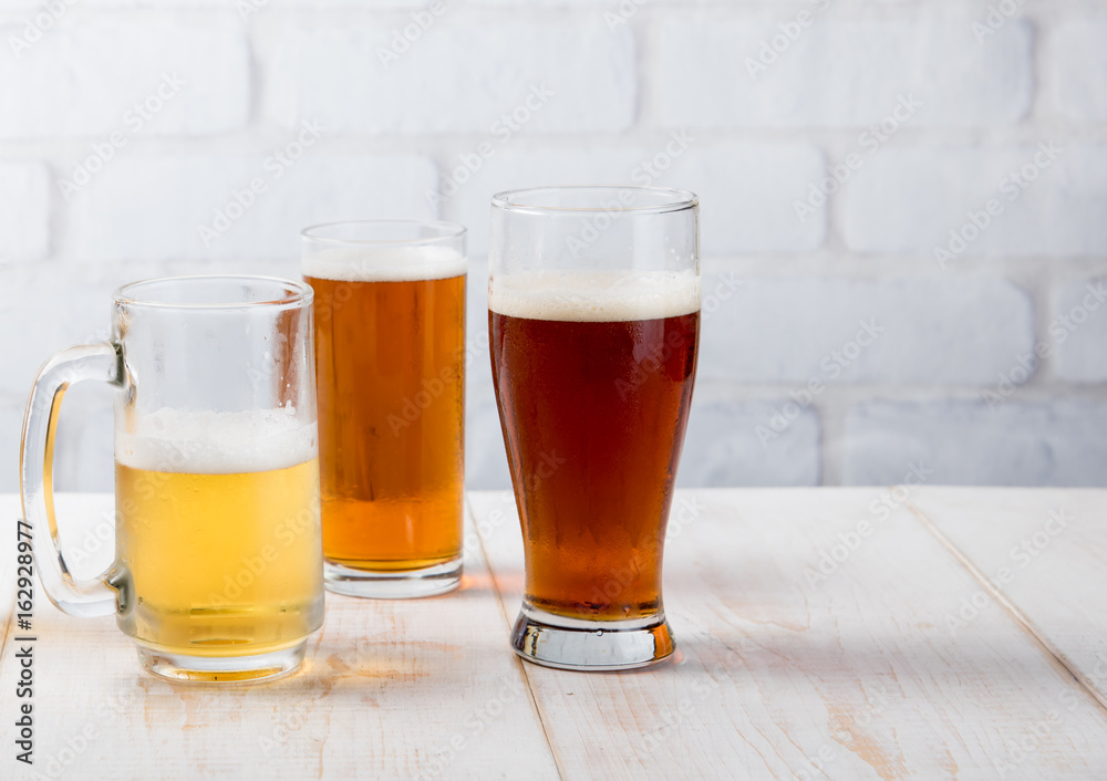 Beer glasses with various beer on wood table against white brick wall Beer glasses with various beer on wood table against white brick wall