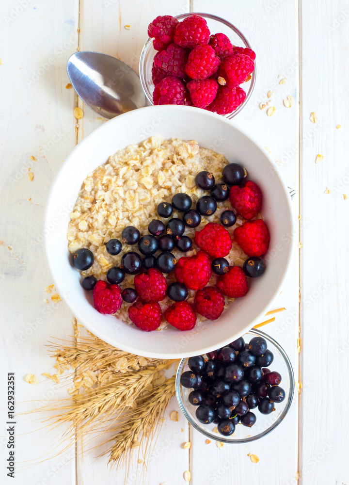 Plate of oatmeal with blueberries and raspberries on white background. Vegetarian breakfast. Plate of oatmeal with blueberries and raspberries on white background. Vegetarian breakfast.