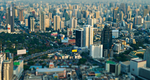 City scape with modern skyscrapers and express way against with slum houses in front of. Bangkok aerial view evening panorama, tilt-shift effect.