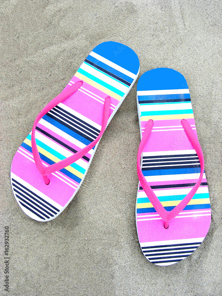 Fototapeta premium Colorful flip-flops on a beach sand 