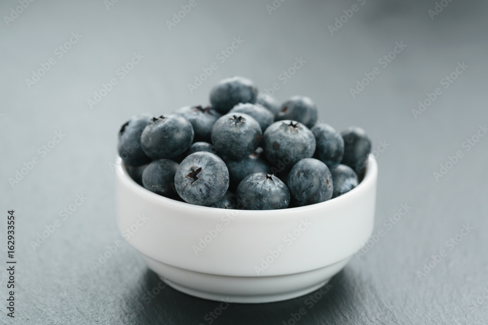 fresh blueberries in white bowl on slate board fresh blueberries in white bowl on slate board