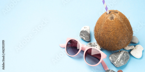 Sun glasses, sea stones and coconut with straw. Travel, sea holiday concept