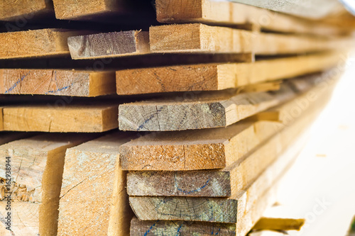 Stack of building lumber at construction site with narrow depth of field. Timber wooden bars.