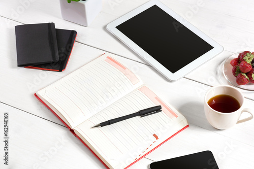 Stylish minimalistic workplace with tablet and notebook and glasses in flat lay style. White background.