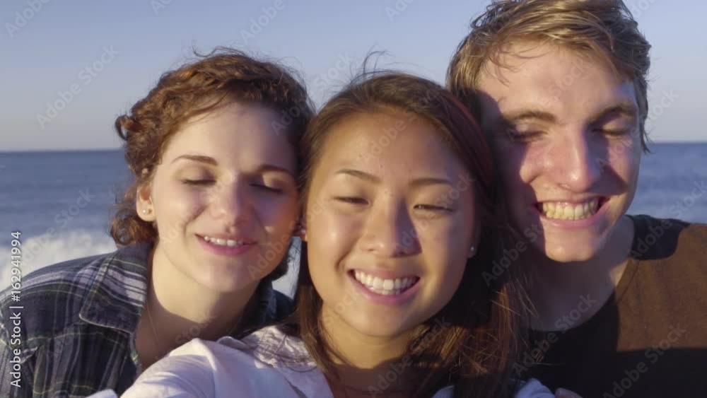 Happy Multiethnic Teens Smile For Selfies On Beach Happy Multiethnic Teens Smile For Selfies On Beach