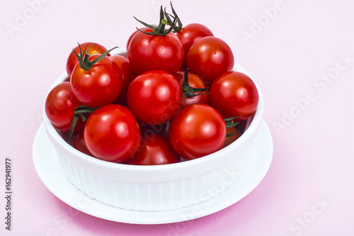Organic cherry tomatoes on pink background.