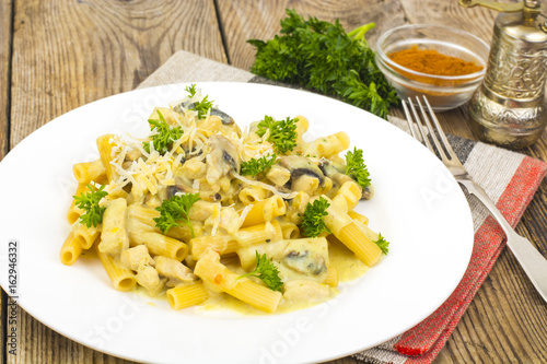 Pasta with creamy cheese sauce and mushrooms on wooden backgroun